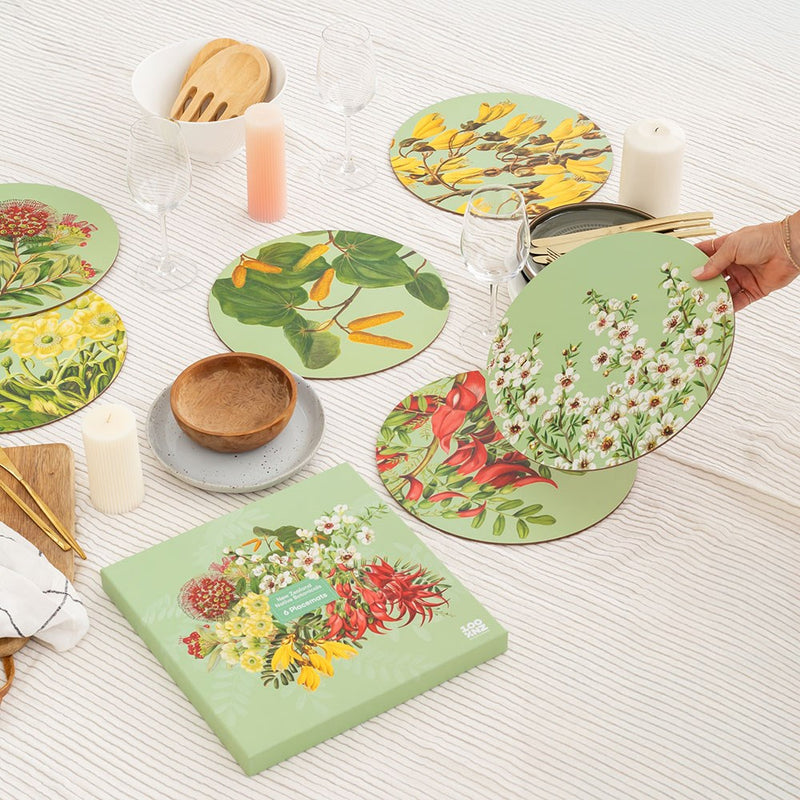 Set of floral placemats on a table with a hand holding one