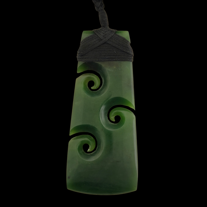 Green jade pendant with spiral designs on a black background
