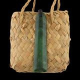 Woven basket with a green stone pendant on a black background