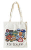An off-white canvas tote bag with long handles, featuring a collage of colorful New Zealand travel patches and the text 'NEW ZEALAND' printed in black at the bottom.