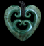 Greenstone heart-shaped pendant with intricate carvings on a black background