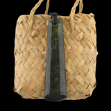 Woven basket with a dark green stone pendant on a black background