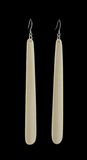 Pair of long, thin, off-white earrings on a black background
