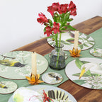 Decorative table setting with floral arrangement and candles on a wooden table.