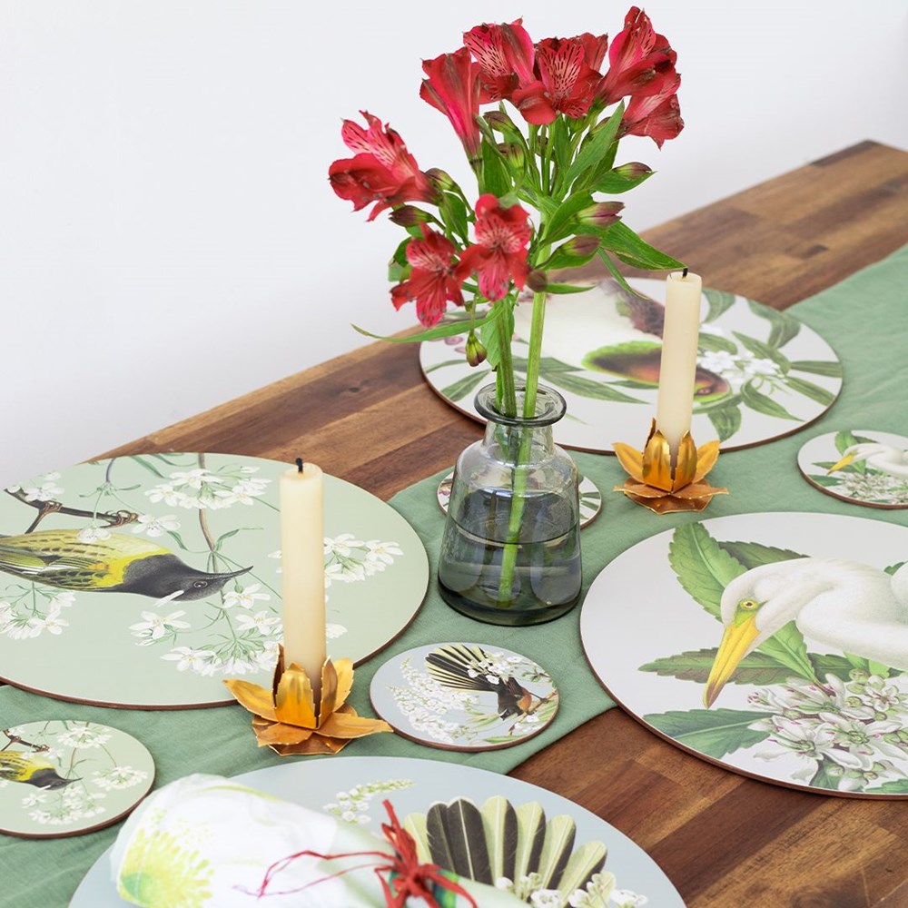 Decorative table setting with floral arrangement and candles on a wooden table.