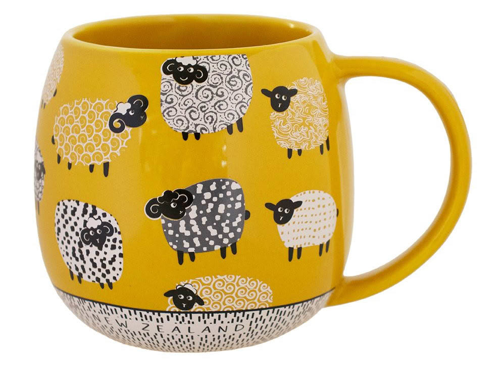 A yellow ceramic mug decorated with a pattern of stylized sheep in black, white, and yellow, featuring 'NEW ZEALAND' printed on the bottom rim.