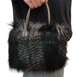 A person holds a large black and gray feather handbag with braided rope handles and iridescent green scale-like accents across the front, against a plain white background.