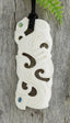 A carved bone necklace with floral and geometric patterns and Paua eyes, displayed on a wooden surface, with an adjustable black cord.