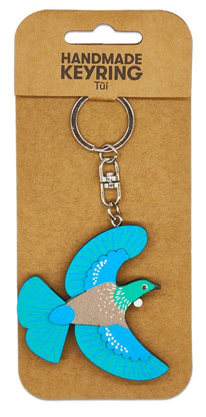 Handmade keyring with a blue bird design on a brown card packaging.