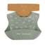 Grey baby bib with nature-themed print and 'New Zealand' text, displayed on a hanger.