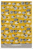 A woven tea towel featuring a repeating pattern of stylized sheep in black, white, and beige on a mustard yellow background, with a textured gray border at the bottom containing the text 'NEW ZEALAND'.