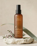 Brown bottle of Wild Ferns Manuka Honey Toning Mist on a beige background with green leaves and flowers.
