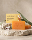 Two bars of Wild Ferns Manuka Honey soap on a stone surface with a beige background