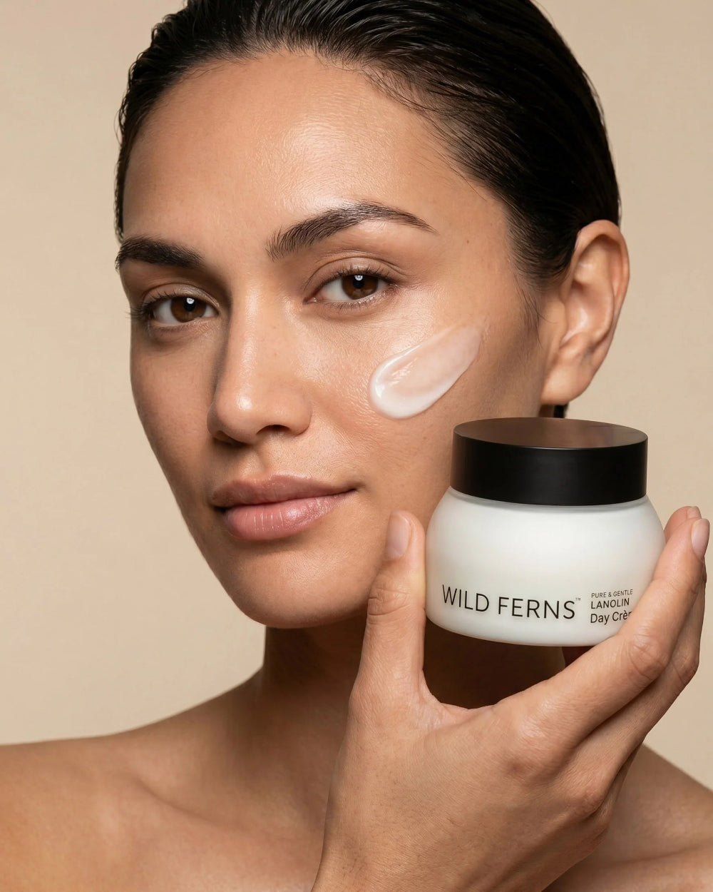Woman holding a jar of Wild Ferns body cream with a visible patch on her face.