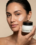 Woman holding a jar of Wild Ferns body cream with a visible patch on her face.