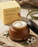 Wild Ferns Manuka Honey Night Crème jar with packaging and flowers on a textured surface