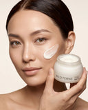 Woman applying cream to her face with a jar of Wild Ferns cream.