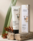 Wild Ferns facial moisturizer tube and packaging on a wooden surface with plants in the background