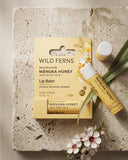 Wild Ferns Manuka Honey lip balm with packaging on a stone surface