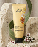 Tube of Wild Ferns Manuka Honey Hand & Nail Creme on a stone surface with flowers and leaves.