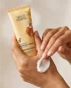 Hand applying Wild Ferns Manuka Honey Hand & Nail Crème to a hand with a beige background