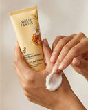 Hand applying Wild Ferns Manuka Honey Hand & Nail Crème to a hand with a beige background