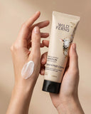 Hand holding a tube of Wild Ferns hand and nail crème with a visible smear on skin against a beige background