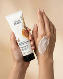 Hand holding a tube of Wild Ferns hand cream with a swatch on another hand against a beige background