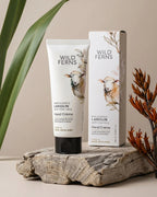 Wild Ferns hand cream and packaging on a wooden surface with plants in the background