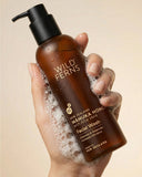 Hand holding a bottle of Wild Ferns Manuka Honey Facial Wash with a beige background