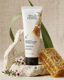 Wild Ferns facial scrub tube with honeycomb and flowers on a neutral background