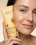 Woman holding a Wild Ferns Manuka Honey Face Mask with visible honeycomb design on a beige background