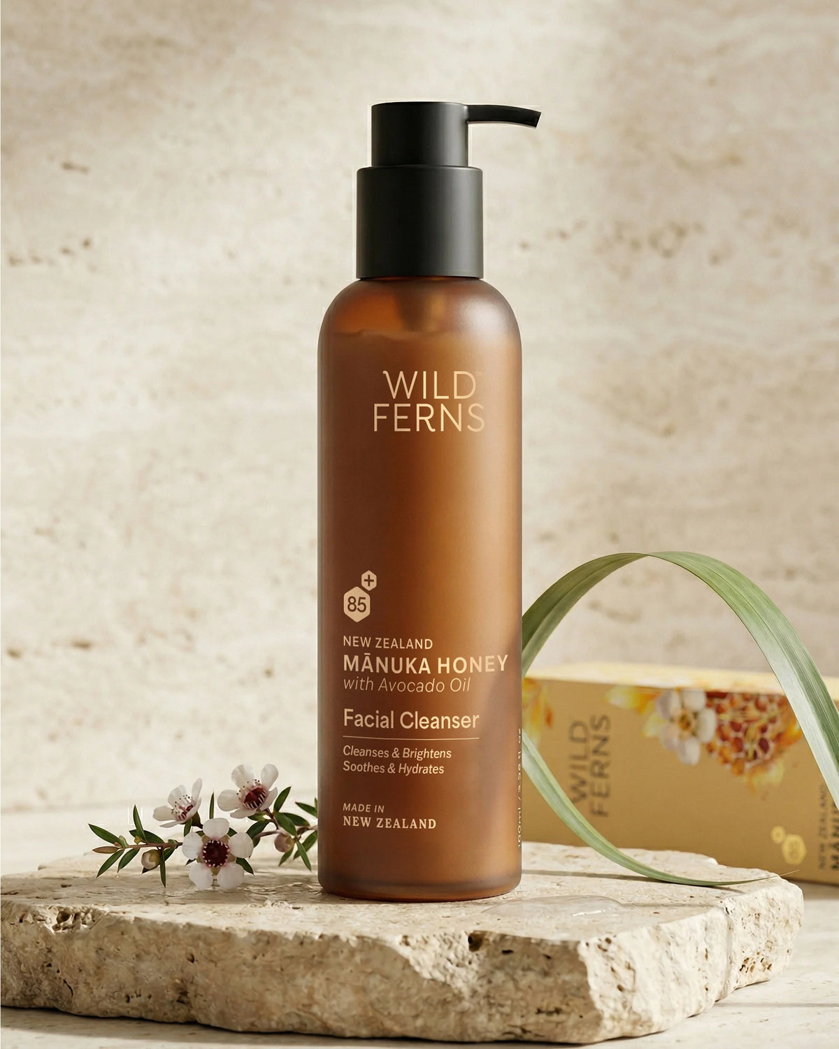 Brown bottle of Wild Ferns Manuka Honey Facial Cleanser on a stone surface with a natural background