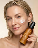 Woman holding a bottle of Wild Ferns skincare product on a beige background
