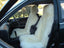 Car interior with white sheepskin seat covers on the driver and passenger seats.