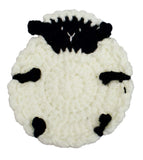 A round, hand-crocheted sheep-shaped item, likely a coaster or decorative mat, featuring a textured off-white body with black yarn details for the face, ears, and markings.