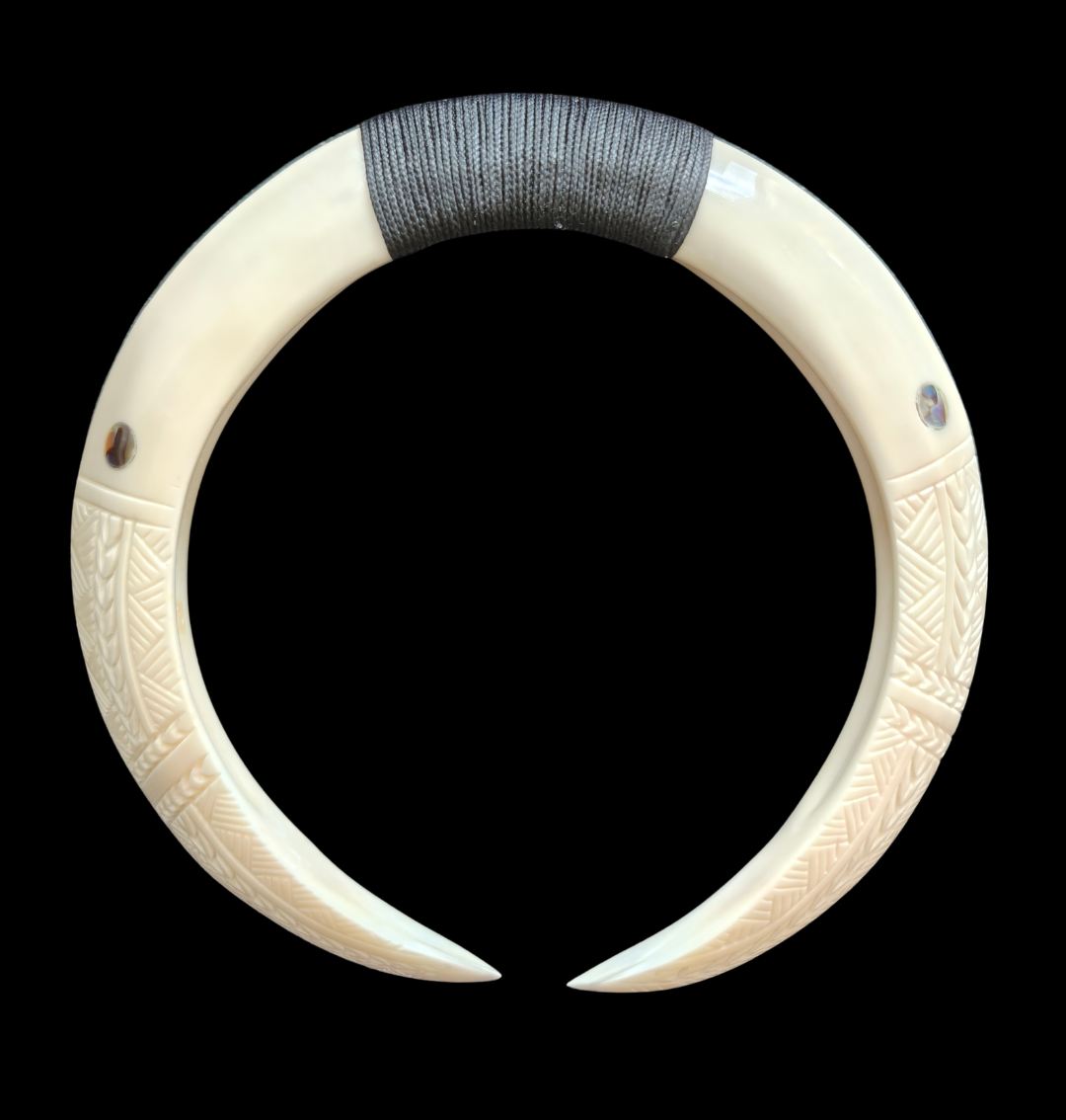 An off-white carved bone or horn collar with geometric patterns and a dark gray wrapped section at the top, shown against a solid black background. Main image