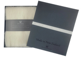 White scarf in a black box with 'Made in New Zealand' label