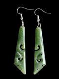 Greenstone earrings with intricate carvings on a black background