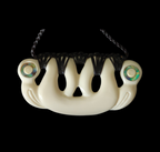 White bone necklace with black cord on a black background