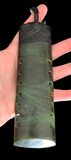 Hand holding a green stone with decorative patterns on a black background
