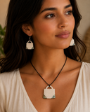 Woman wearing a necklace and earrings with a neutral background