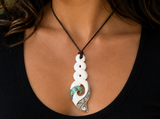 Necklace with a white pendant featuring a spiral design on a person wearing a black top.