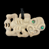Carved bone pendant with green eyes on a black background