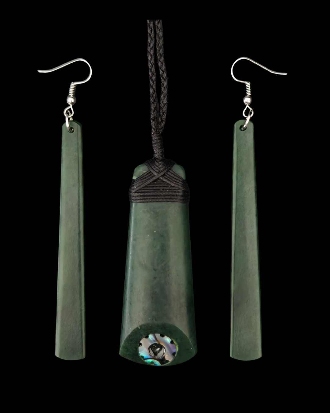 Greenstone jewelry set featuring a central pendant and two matching drop earrings on a solid black background. The central pendant is a tapered greenstone piece with a dark braided cord wrap and a small iridescent shell inlay near the bottom.