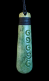 Greenstone pendant with spiral designs on a black background