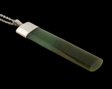 A greenstone cylindrical pendant necklace with a polished silver-toned cap and a silver ball chain, shown against a solid black background.