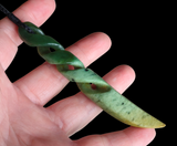 Hand holding a green jade necklace against a black background