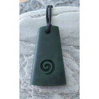 Green pendant with spiral design on a stone surface