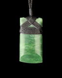 Green jade pendant with woven cord on a black background